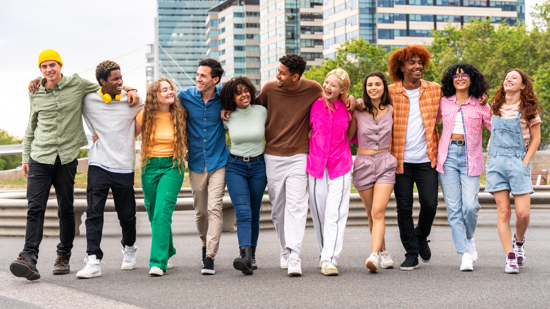 Grupo de jovenes caminando abrazados y sonriendo